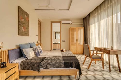 a bedroom with a bed and a table and a desk at Casa Solace 3 BHK by tisyastays in Assagao