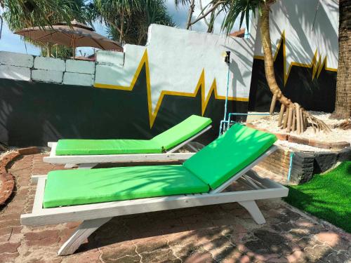 a pair of green lounge chairs on a patio at Beach Home Lanta in Ko Lanta