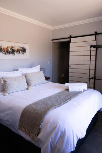a bedroom with a large bed with white sheets and pillows at The Cottage Unit in Kathu