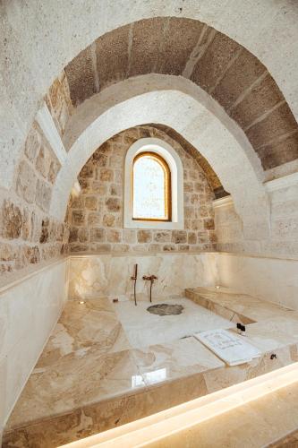 a room with a stone wall and a window at Via Regia Cappadocia Hotel in Uchisar