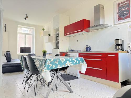 une cuisine avec des placards rouges et une table avec des chaises dans l'établissement Maison cosy 3 chambres proche toutes commodités, à Croix