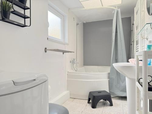 La salle de bains blanche est pourvue d'une baignoire, de toilettes et d'un lavabo. dans l'établissement Maison cosy 3 chambres proche toutes commodités, à Croix
