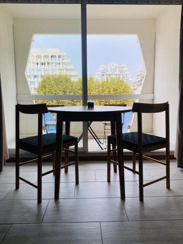 une table et des chaises dans une pièce avec une fenêtre dans l'établissement Studio La Grande Motte, au plus près des plages, à La Grande Motte