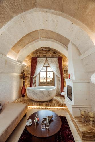 a large bathroom with a tub and a table at Via Regia Cappadocia Hotel in Uchisar