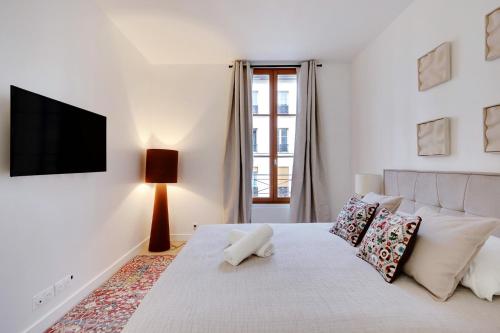 - une chambre blanche avec un lit et une télévision murale dans l'établissement Boutiques Apartments Paris, à Paris