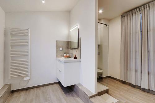 La salle de bains est pourvue de murs blancs, d'un lavabo et d'un miroir. dans l'établissement Boutiques Apartments Paris, à Paris