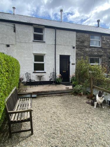ein Haus mit einer Bank und einem Hund davor in der Unterkunft HOLIDAY HOUSE TANYGRISIAU SNOWDONIA North Wales in Tanygrisiau