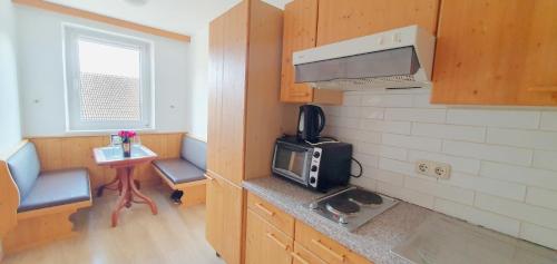 a small kitchen with a microwave and a small table at Restaurant Athen & Appartements Bergen in Bergen