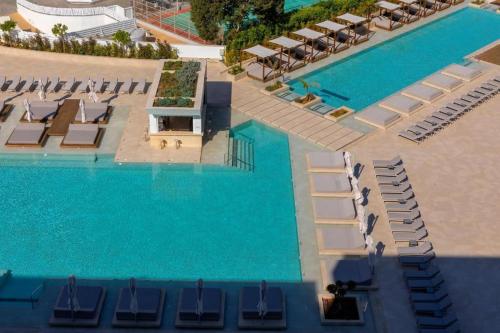 an overhead view of a pool with lounge chairs and water at The HEALTHY Stay-Padel, Pool&Fitness in Ayia Napa