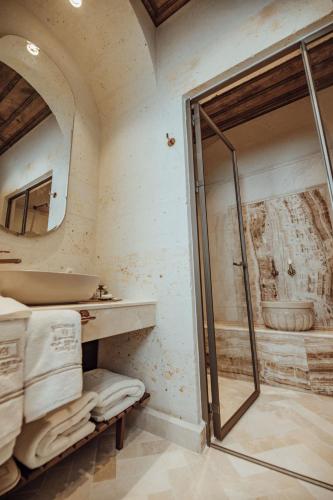 a bathroom with a shower and a sink and a mirror at Via Regia Cappadocia Hotel in Uchisar
