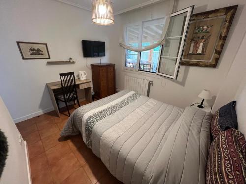 a bedroom with a bed and a desk and a window at Habitación con baño privado y jardín Cerca de las playas in Boó de Piélagos
