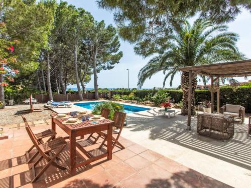 a patio with a table and chairs next to a pool at Villa Platja Calafato by Interhome in L'Ametlla de Mar