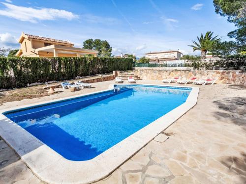 a swimming pool in a yard with chairs and a house at Villa Africa by Interhome in L'Ametlla de Mar