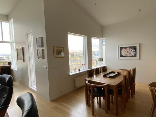 a dining room with a table and some windows at Beautiful and Luxurious Oceanfront Apartment in Garðabær