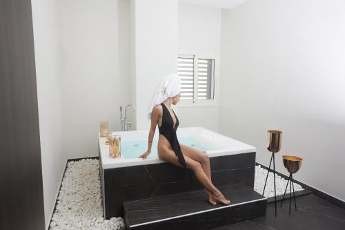 a woman sitting in a bath tub with a towel on her head at The HEALTHY Stay-Padel, Pool&Fitness in Ayia Napa