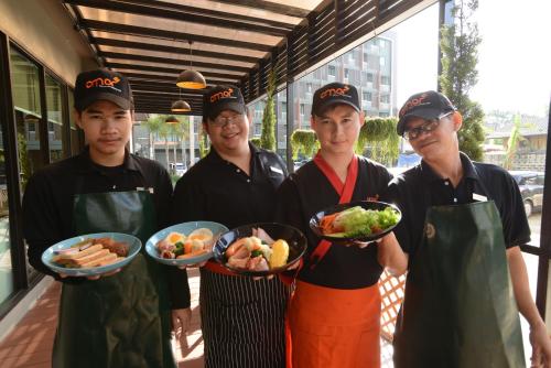 a group of four men holding plates of food at Cmor by Recall Hotels SHA Extra Plus in Chiang Mai