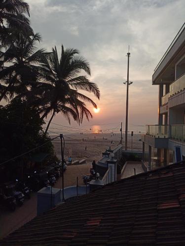 a view of a beach with a palm tree and the sunset at holiday homes in Murud