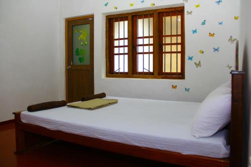 a bedroom with a white bed with a window and a window at Kandy Little White House in Kandy