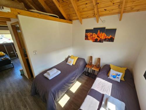 two beds in a room with wood ceilings at Patagonia Tiny House in El Chalten