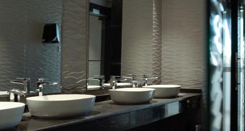 a bathroom with four sinks and a mirror at La Zona Continental Hotel in Dubai