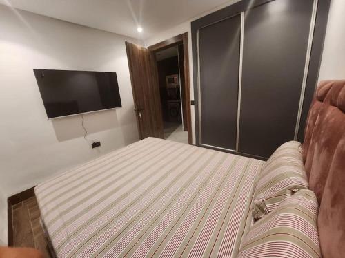 a bedroom with a bed and a flat screen tv at Élégance urbaine, Gueliz central in Marrakech
