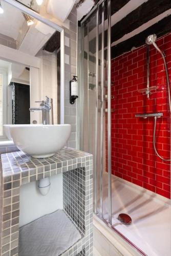 La salle de bains est pourvue d'un lavabo et d'un mur en briques rouges. dans l'établissement Opéra Paris center Charming air-conditioned loft, à Paris