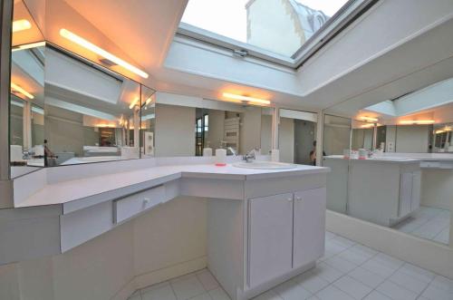 La grande salle de bains est pourvue d'un lavabo et d'un grand miroir. dans l'établissement Grande Pomme, à Paris