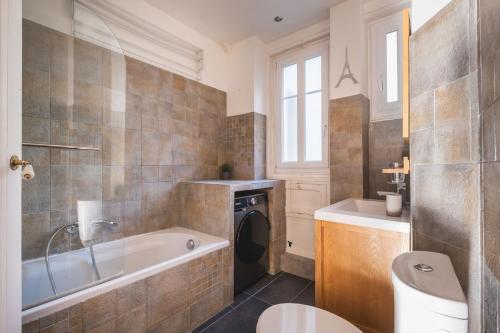 une salle de bain avec baignoire et machine à laver dans l'établissement Logement Haut de Gamme à Grenelle, à Paris
