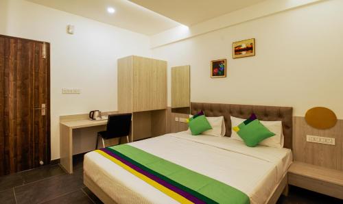 a bedroom with a bed with a desk and green pillows at Itsy Hotels Silver Keys in Bengaluru