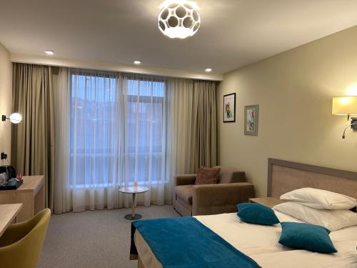 a hotel room with two beds and a chair and a window at Hotel Siesta in Užice