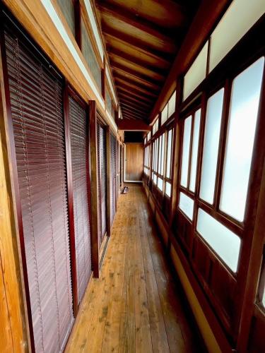 an empty hallway with windows and a wooden floor at 島宿糸 in Iki