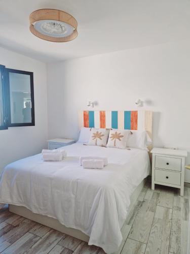 a white bedroom with a large white bed with two pillows at Villa Mirakai in Playa Honda