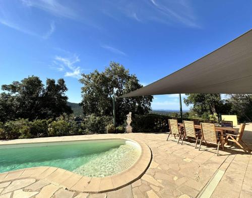 une piscine avec deux chaises et un parasol dans l'établissement Villa Myosotis pour 8 personnes avec piscine chauffée et vue mer à La Londe-Les-Maures, à La Londe-les-Maures