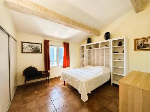 une chambre avec un lit et une chaise dans une pièce dans l'établissement Villa Myosotis pour 8 personnes avec piscine chauffée et vue mer à La Londe-Les-Maures, à La Londe-les-Maures