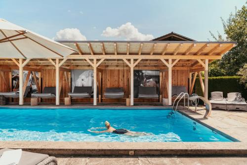 a woman swimming in a swimming pool in a house at Staudacherhof in Garmisch-Partenkirchen I Blick aufs Zugspitzmassiv I einzigartige Bayurvida Küche in Garmisch-Partenkirchen