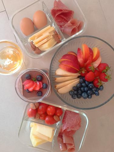 vier Plastikbehälter, gefüllt mit verschiedenen Käsesorten und Früchten in der Unterkunft Room Ghetto in Korčula