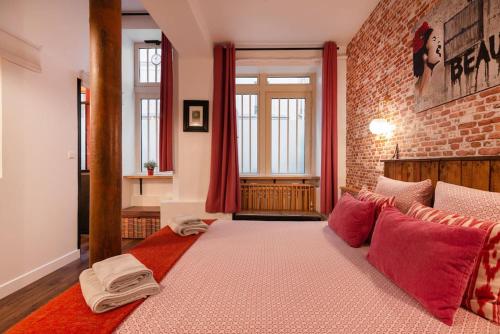 une chambre avec un grand lit avec des oreillers rouges dans l'établissement Montmartre Rue des Martyrs Loft with AC, 4-7 PEO, à Paris