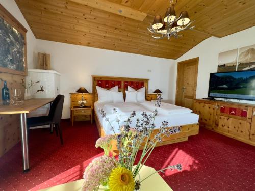 a bedroom with a bed and a table and a tv at Landhaus Lechthaler in Sankt Anton am Arlberg