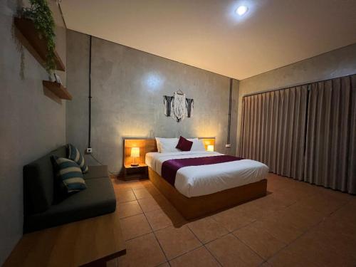 a bedroom with a bed and a chair in it at Keramas temuku family Guest house in Gianyar