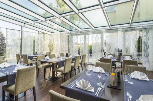 a restaurant with tables and chairs and glass ceilings at Taste Hotel Heidenheim in Heidenheim