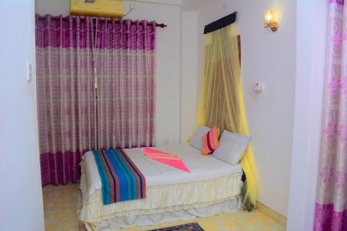 a small bed in a room with purple curtains at Tissa Rainbow Guest & Yala in Tissamaharama