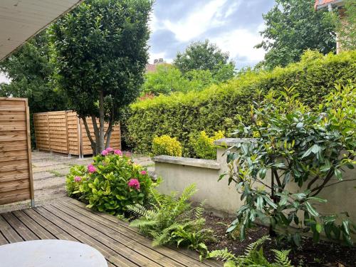 un jardin avec une terrasse en bois ornée de fleurs et de plantes dans l'établissement studio tout equipe, à Rueil-Malmaison