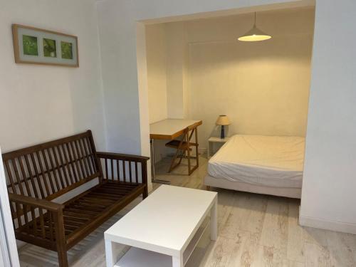 - une chambre avec un lit, un banc et une table dans l'établissement studio tout equipe, à Rueil-Malmaison