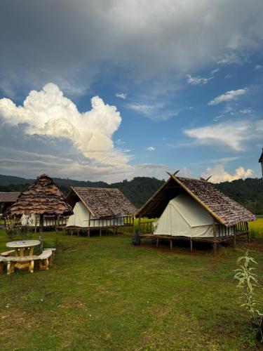 un grupo de tiendas de campaña en un campo con una mesa en Khaodoihomestay&foods, en Ban Na Pa Paek
