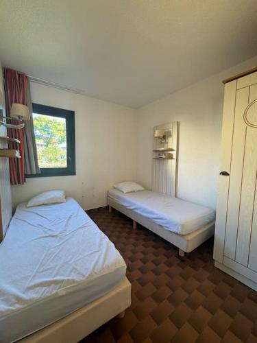 une chambre avec deux lits et une fenêtre dans l'établissement Appartement - Cap d'Agde, au Cap d'Agde