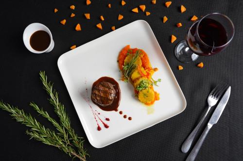 a white plate with food and a glass of wine at Sataya Resort Marsa Alam in Marsa Alam City
