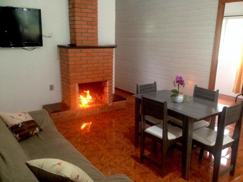 a living room with a table and a fireplace at Kantinho da Serra in Nova Petrópolis
