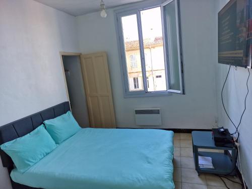 une chambre avec un lit avec des oreillers bleus et une fenêtre dans l'établissement Chez Michel, à Marseille