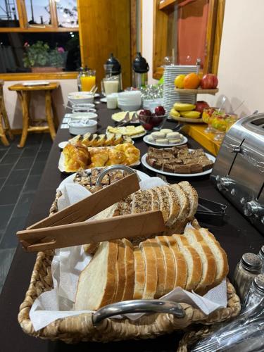 a table topped with lots of bread and other foods at Hotel y Cabañas Casa de Piedra in Trevelin