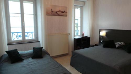 a bedroom with two beds and two windows at Hotel La Renaissance in Cherbourg en Cotentin